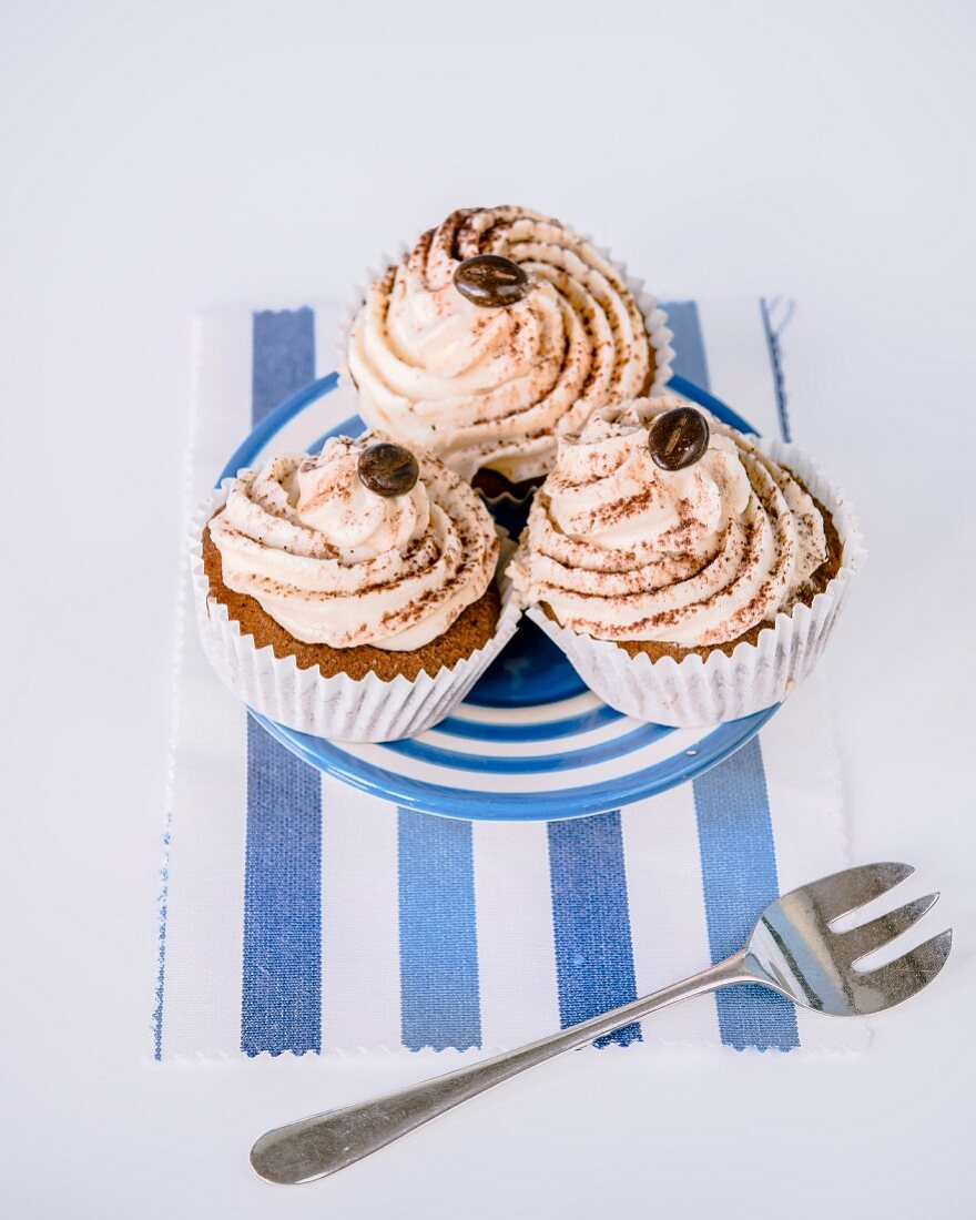 Cupcakes mit Buttercreme, Kakaopulver und Mokkabohne