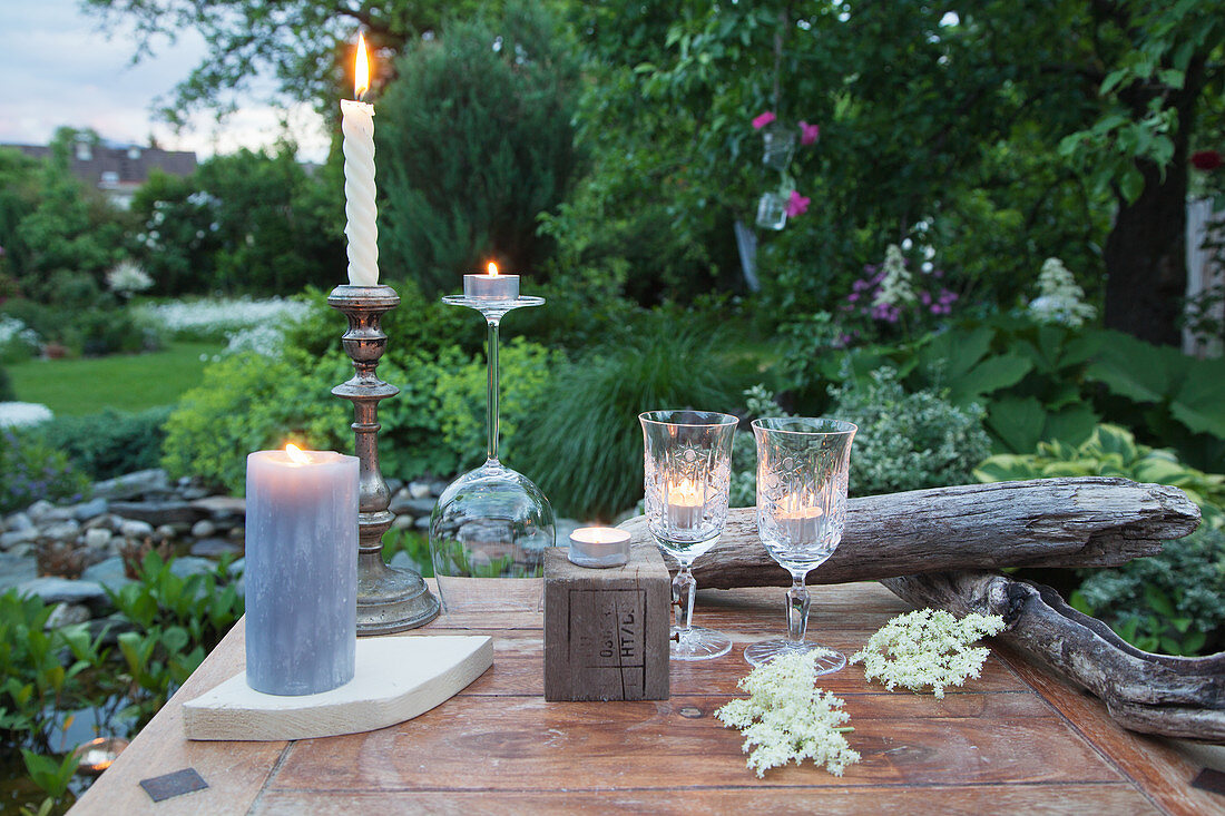 Mit Kerzen und Windlichtern gedeckter Tisch im Garten