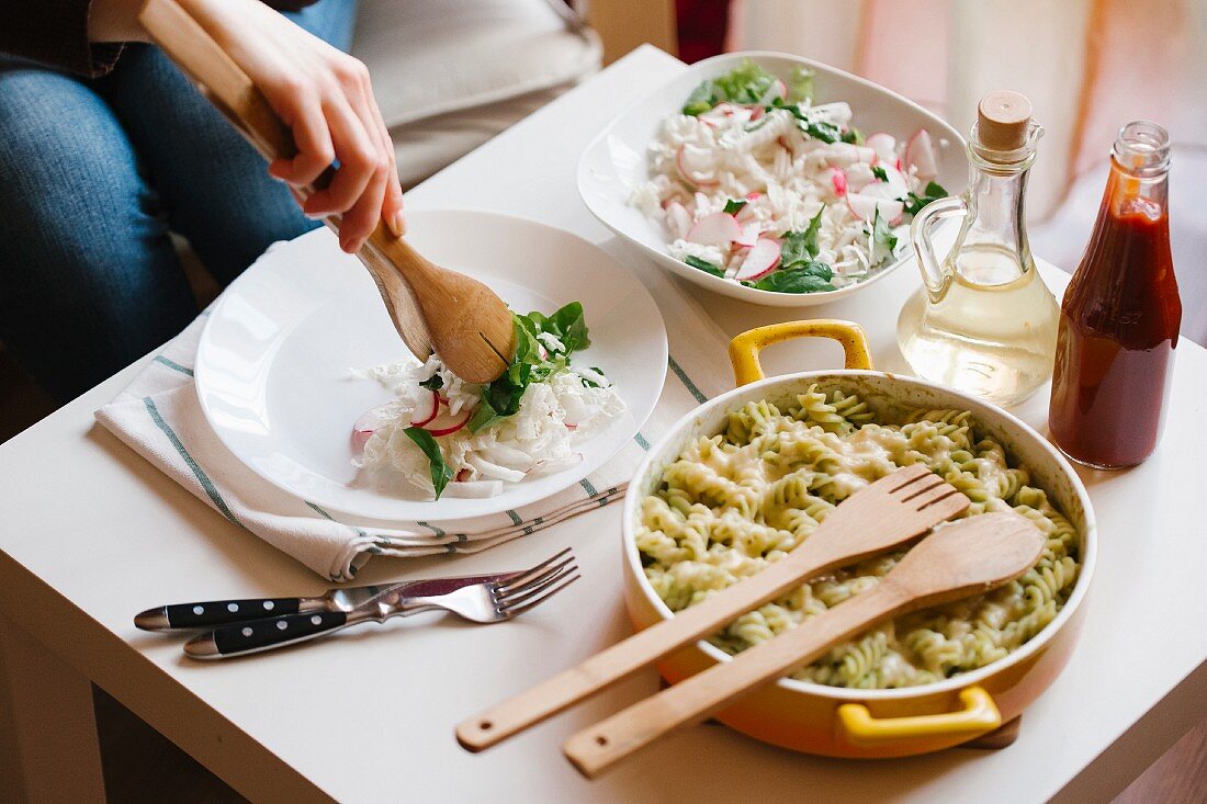 Frau serviert Salat mit Holzzange