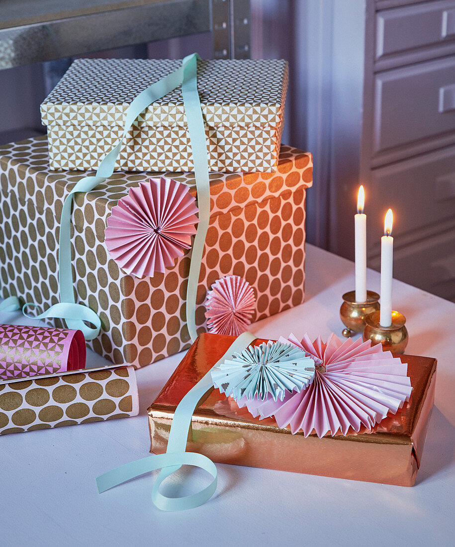 Verpackte Geschenke mit Metallic-Papier und Rosetten als Deko