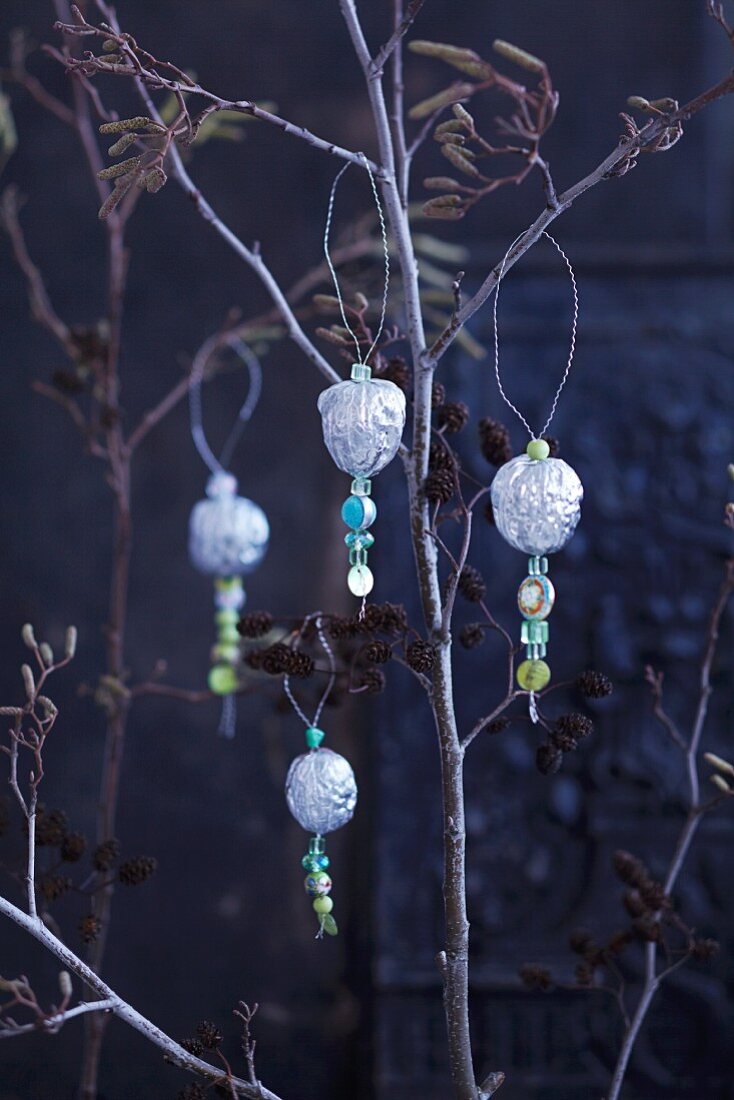 Silberne Walnüsse mit Dekoperlen auf Zweigen als Weihnachtsdeko