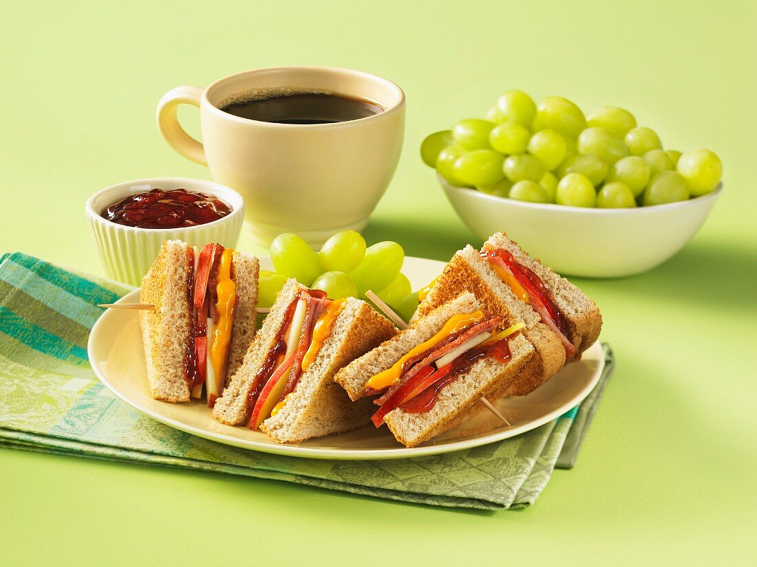 Club sandwich with apple, cheese and chutney, served with grapes and a cup of coffee