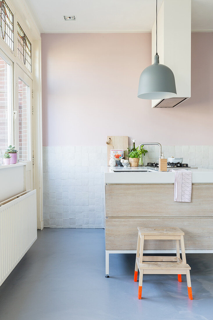 Stool with bright orange legs in modern kitchen in pastel shades