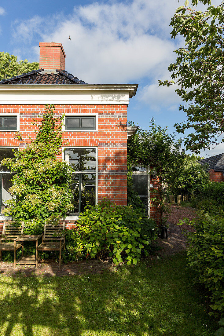 Sommerlicher Garten um ein kleines Backsteinhaus