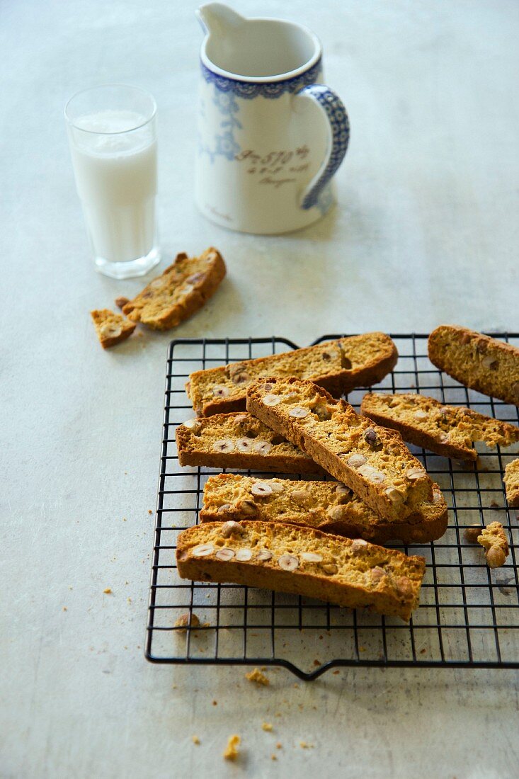 Hazelnut biscotti on a wire cooling rack in front of a glass of milk