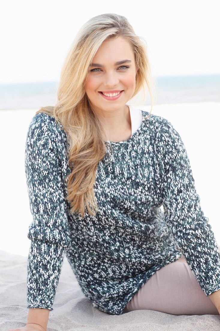 A young blonde woman wearing a grey and white knitted jumper