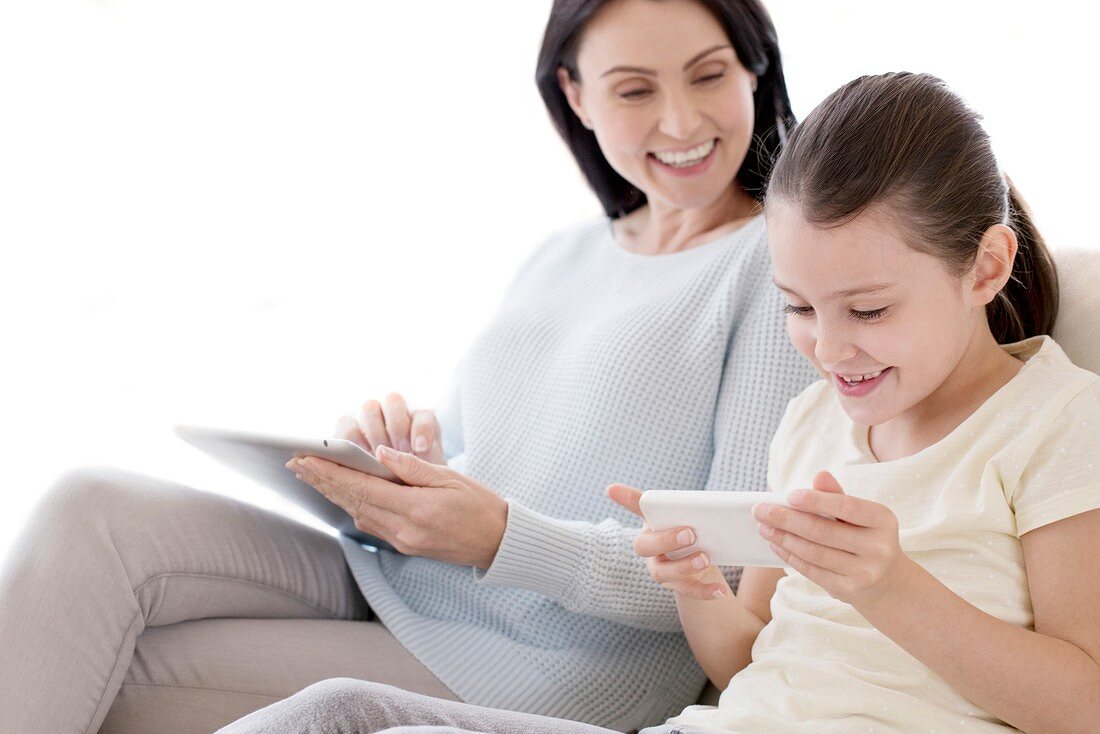Mother and daughter with tablet and phone