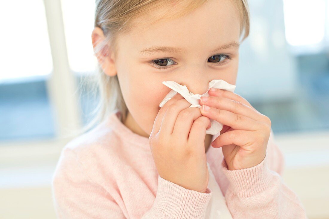 Young girl wiping nose on tissue