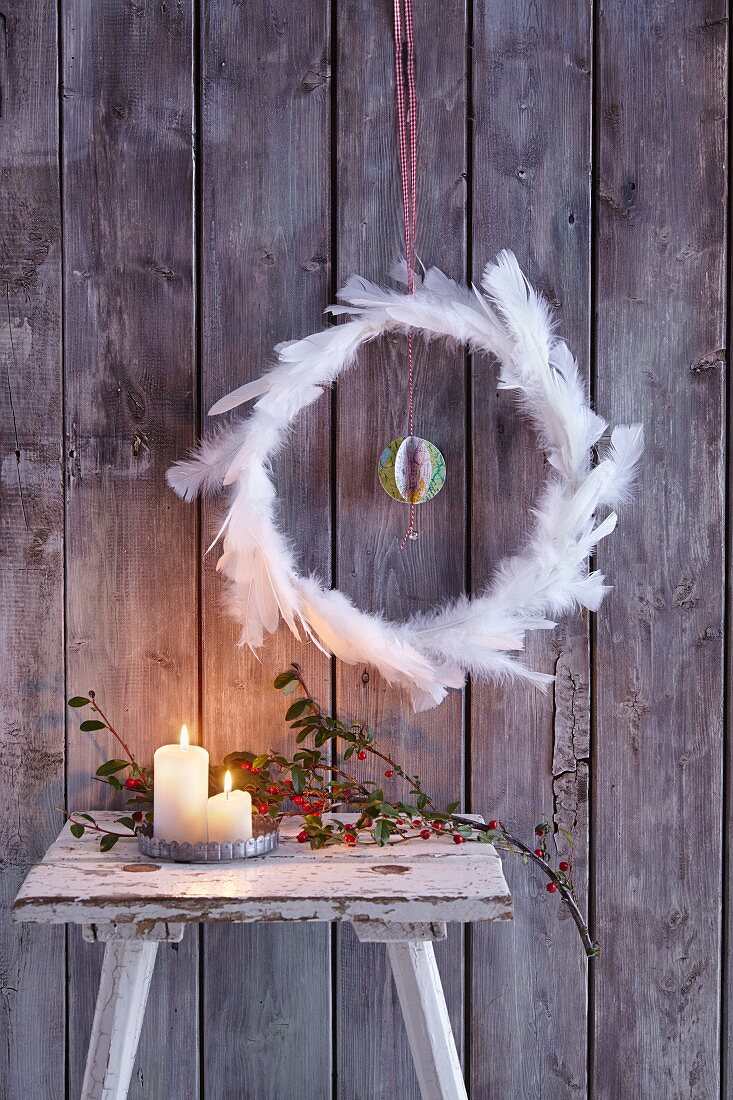 Festive wreath of feathers with central bauble made from maps