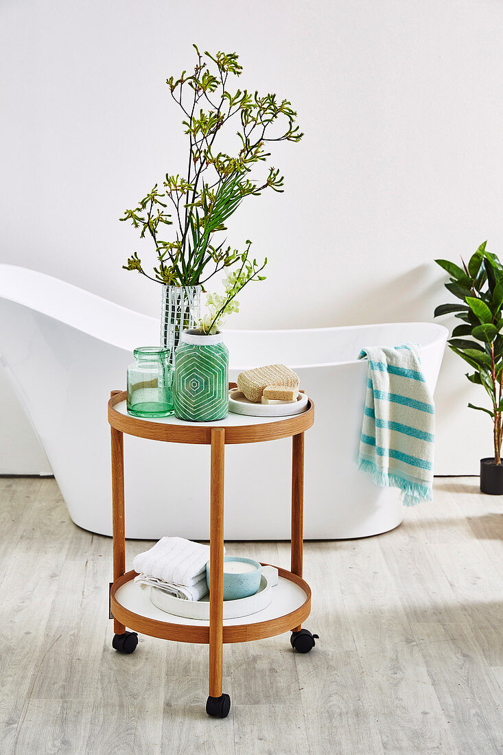 Round side table on castors in front of a free-standing bathtub