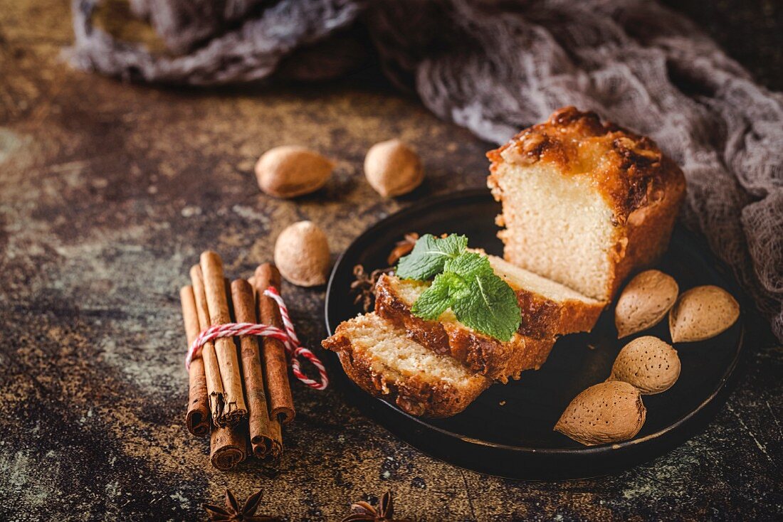 Homemade cinnamon cake and almonds on dark table