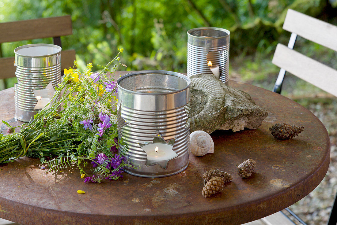 DIY-Windlichter aus Konservendosen auf rostigem Gartentisch