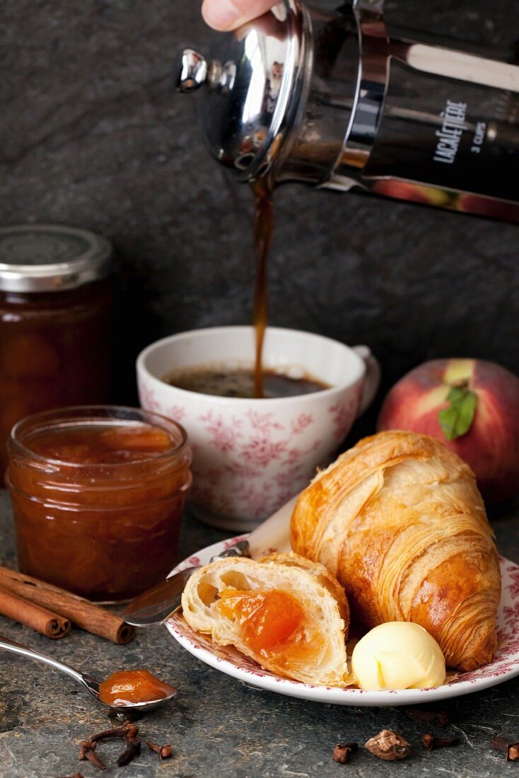 Frühstück mit Kaffee, Croissant, Pfirsichmarmelade und Butter