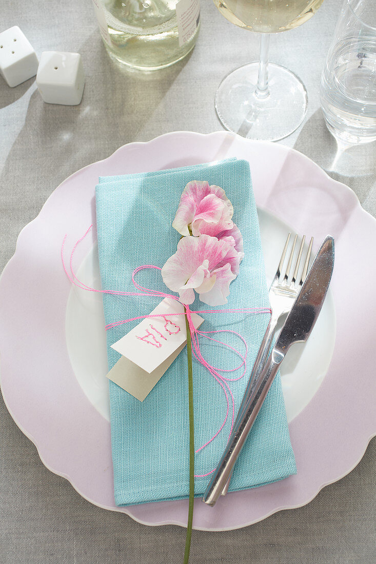 Place setting with pale blue linen napkin, flower and name card