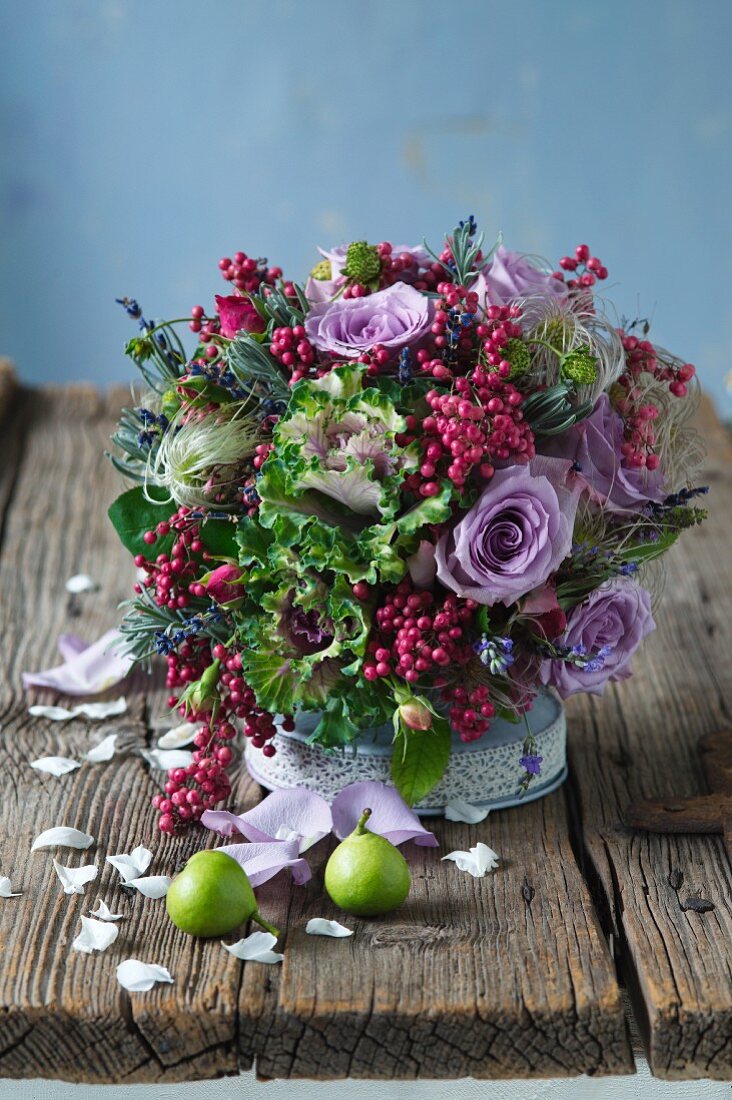 Colourful arrangement of purple roses, ornamental cabbage and pink pepper