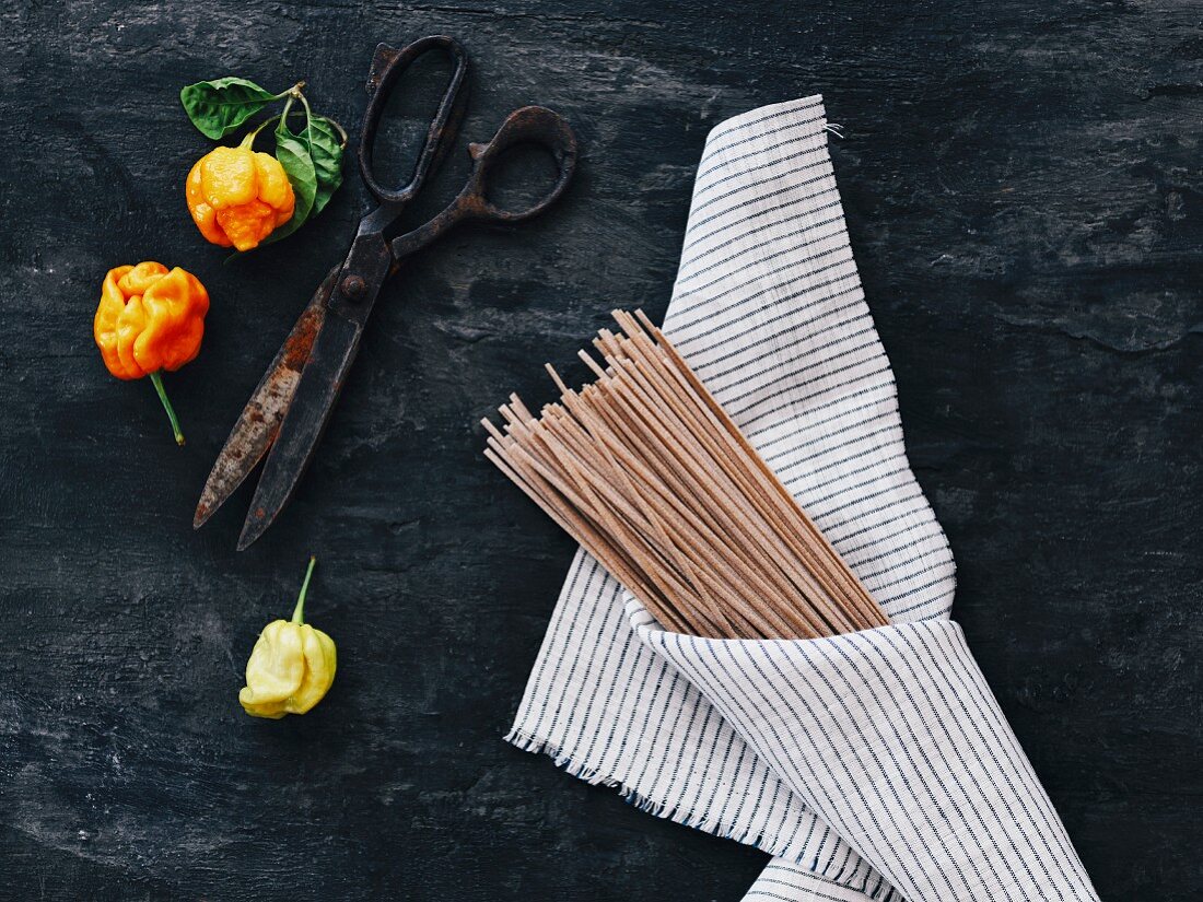 Uncooked whole-wheat fettucine wrapped in a cloth on a black background