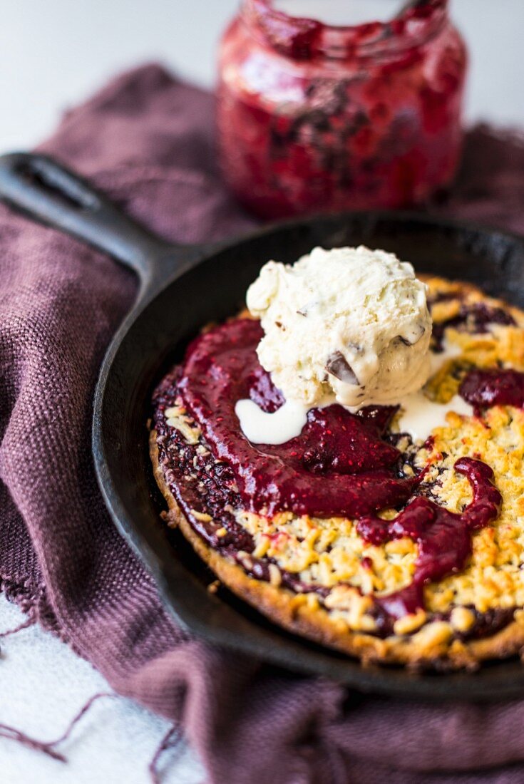 A skillet cookie with jam and vanilla ice cream