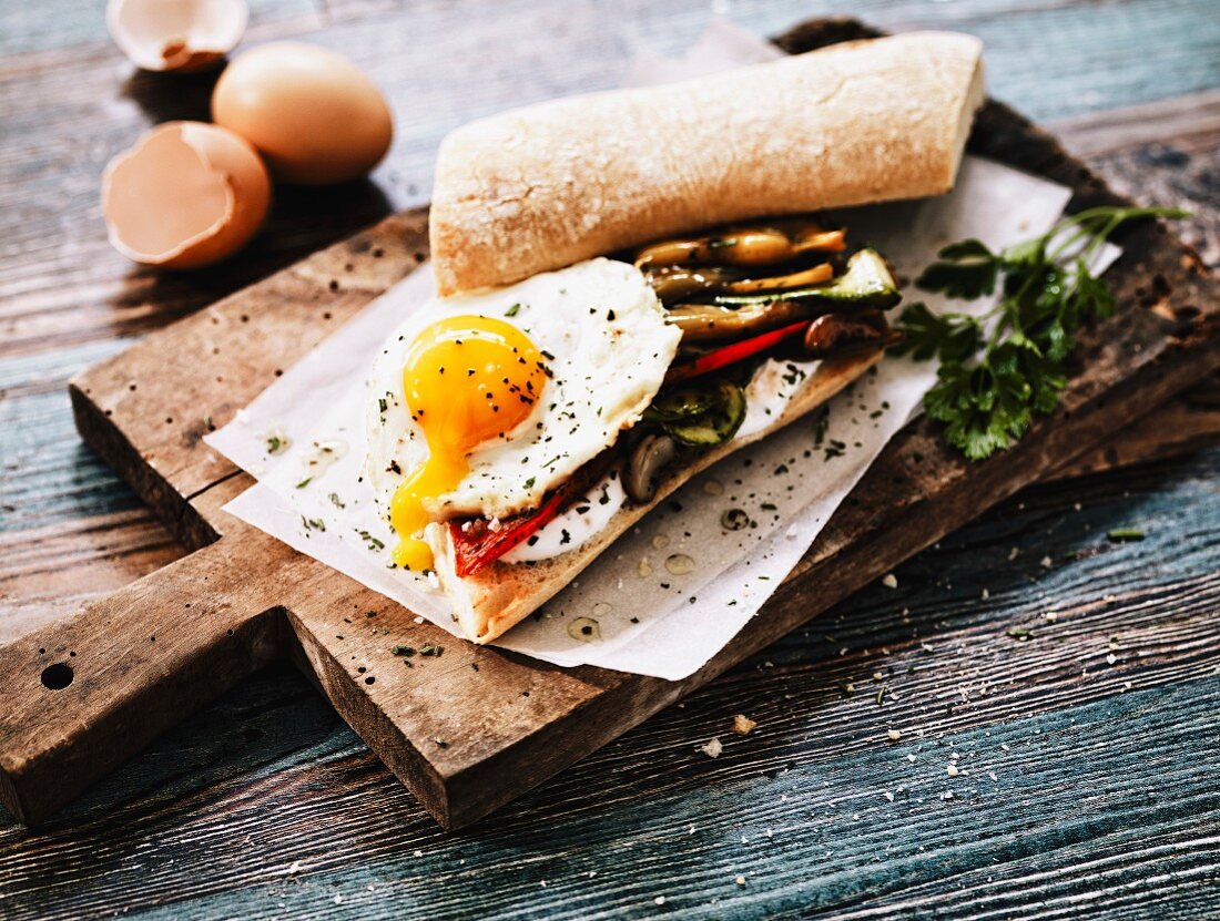 A vegetarian sandwich with grilled vegetables and a fried egg