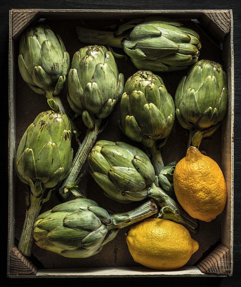 Artichokes and lemons in a small wooden crate