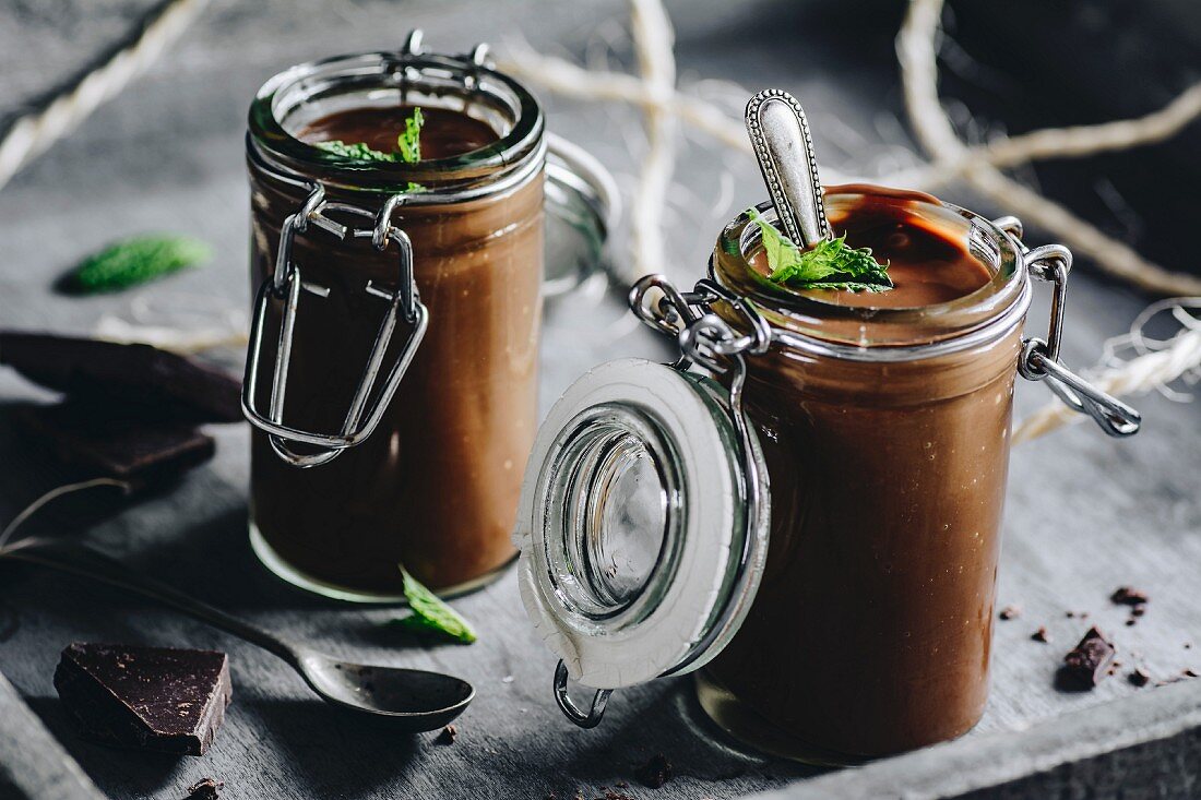 Chocolate pudding decorated with mint leaves and dark chocolate in glass jars
