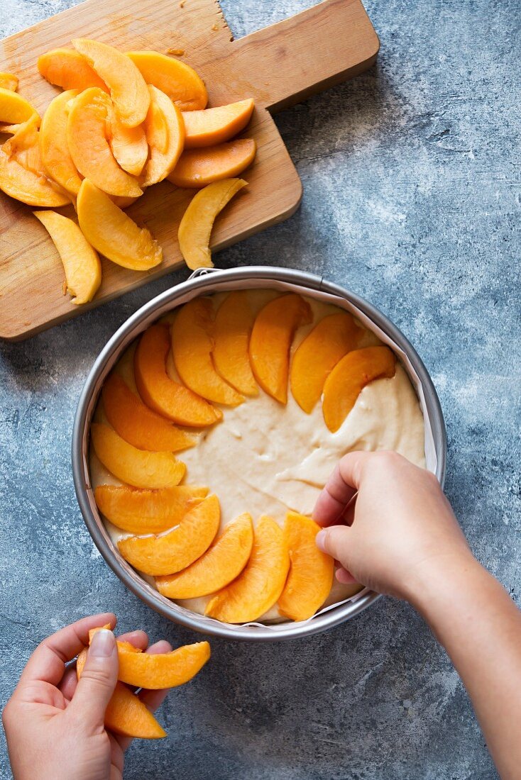 Pfirsichkuchen zubereiten: Kuchen mit Pfirsichspalten belegen