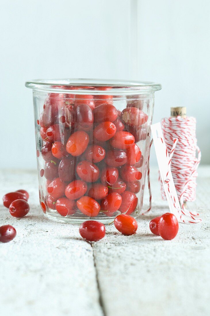 Freshly picked Cornelian cherries in a glass jar on a rustic wooden table