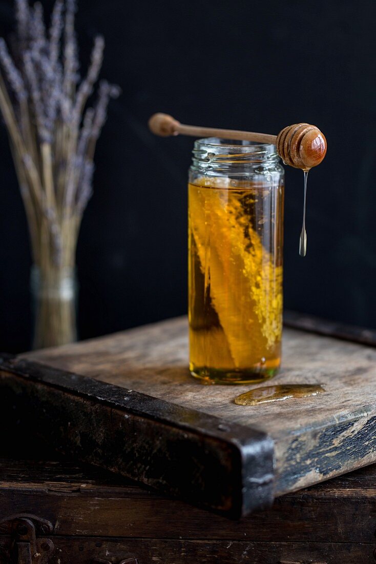 A jar of honey with honeycomb and a honey spoon