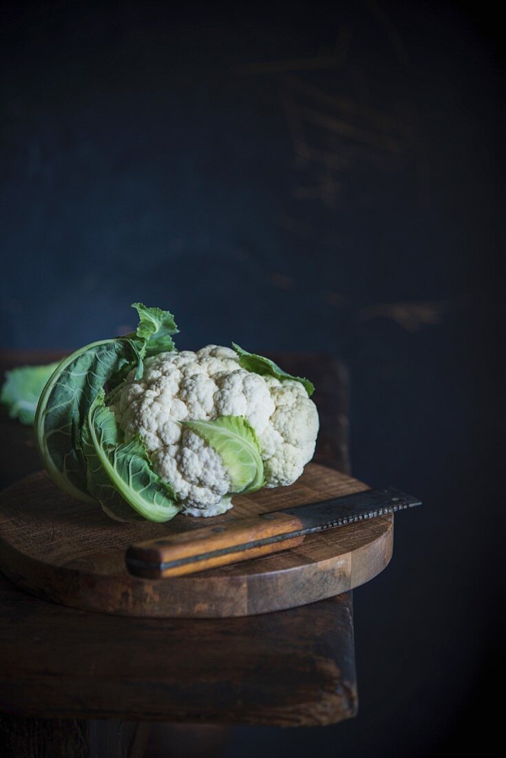 Cauliflower and a knife on a wooden table