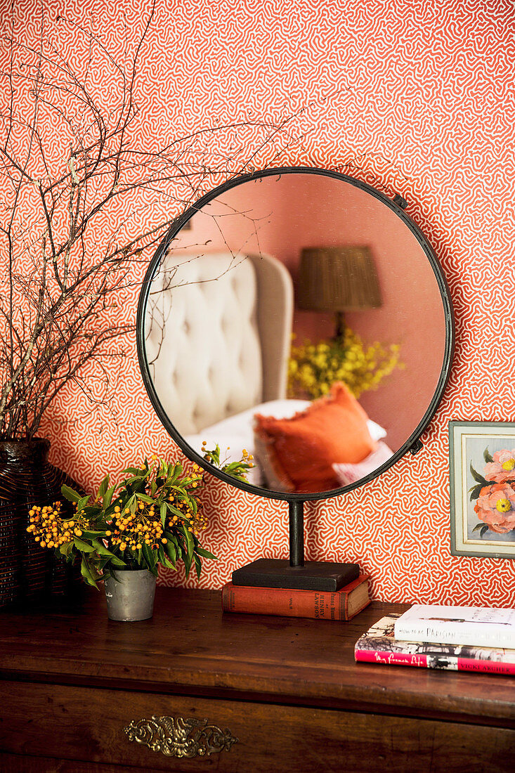 Round standing mirror in the bedroom with patterned wallpaper