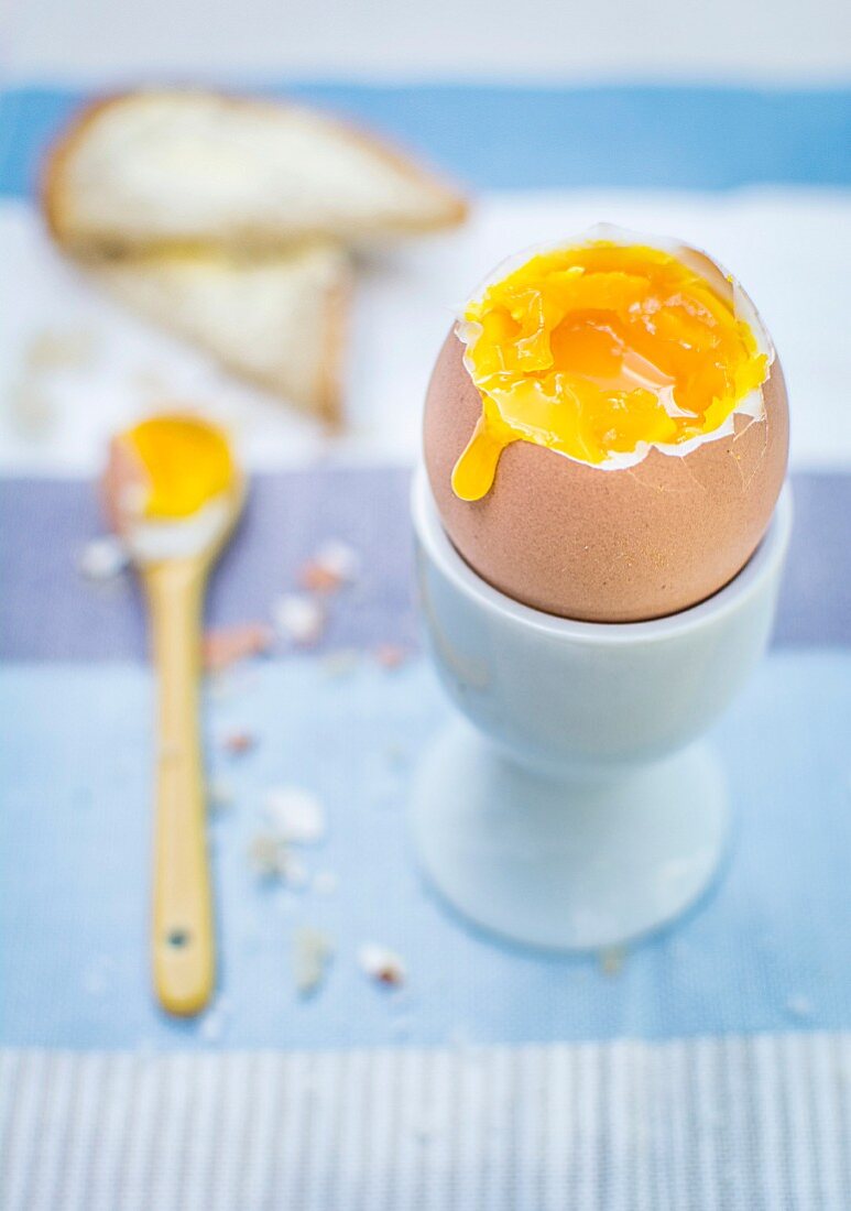 Soft Boiled Egg in an Egg Cup with Topped Cracked Off and Yolk Running Over