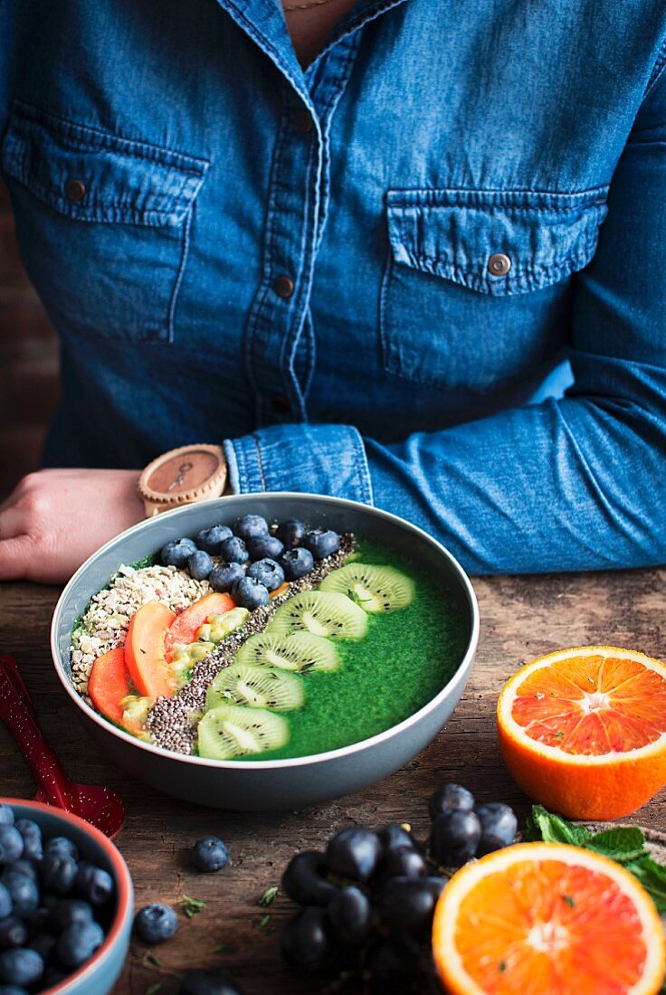 Smoothie Bowl mit Kiwi, Orange, Heidelbeeren, Chiasamen und Haferflocken