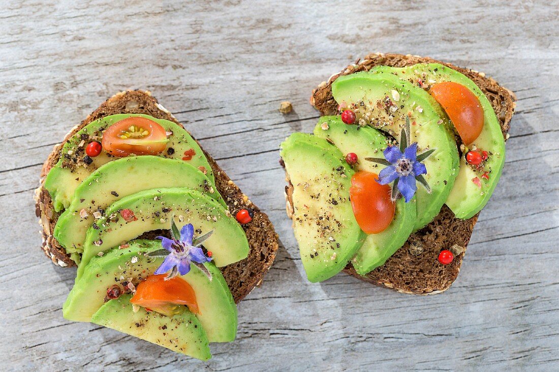 Wholegrain bread topped with avocado slices, tomato and borage flowers