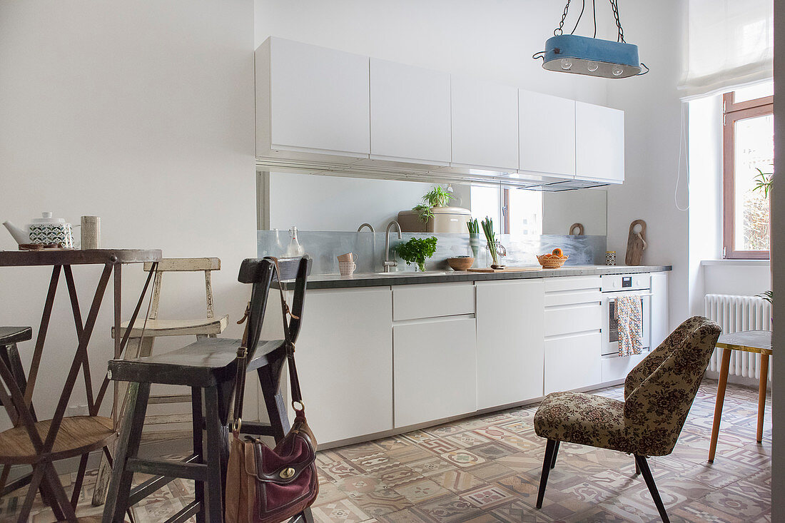 weiße Küchenzeile, ein Polsterstuhl und Bistrotisch mit Hockern in der Küche