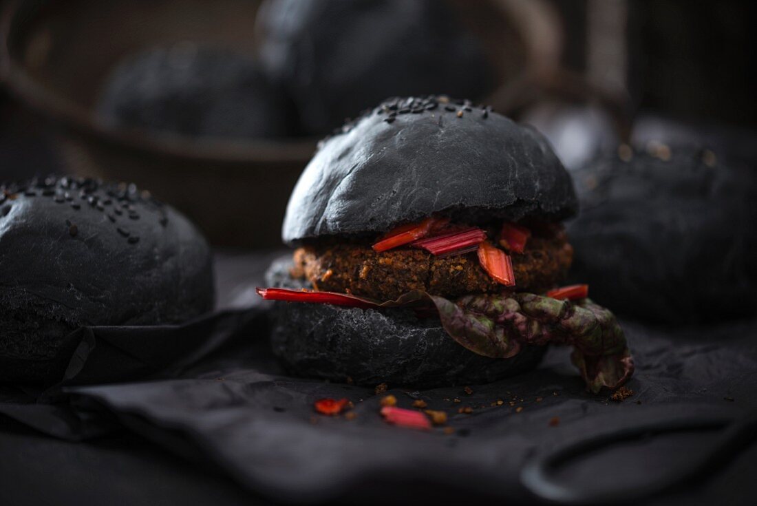 A vegan patty with red chard and salsa in a black burger bun