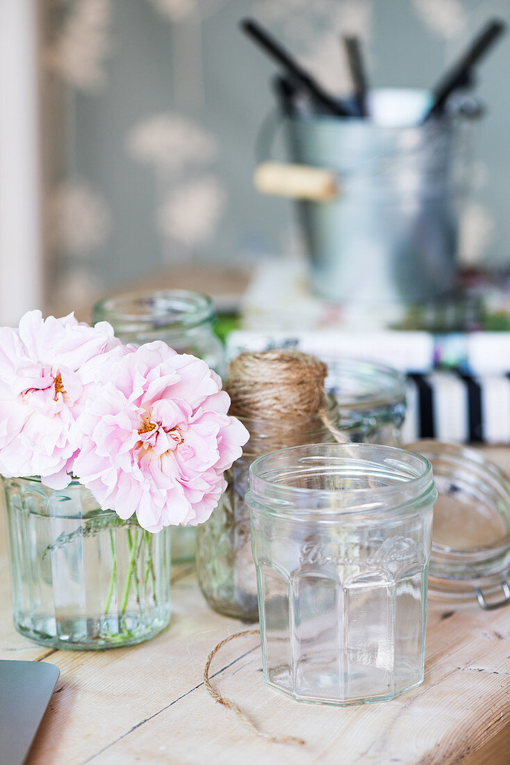 Einmachglas und rosa Blume auf Holztisch