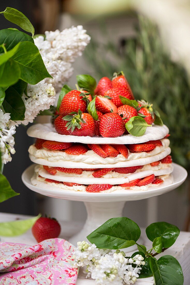 A meringue and cream layered cake with strawberries and basil