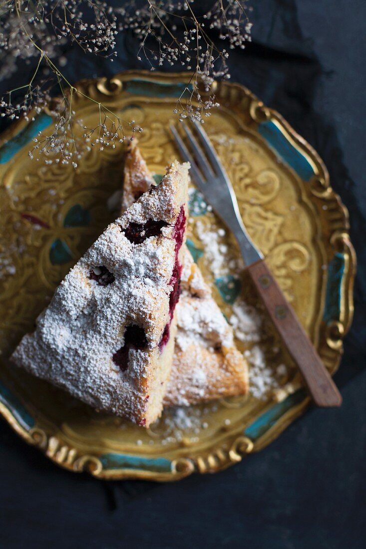 Zwei Stücke Brombeerkuchen mit Puderzucker