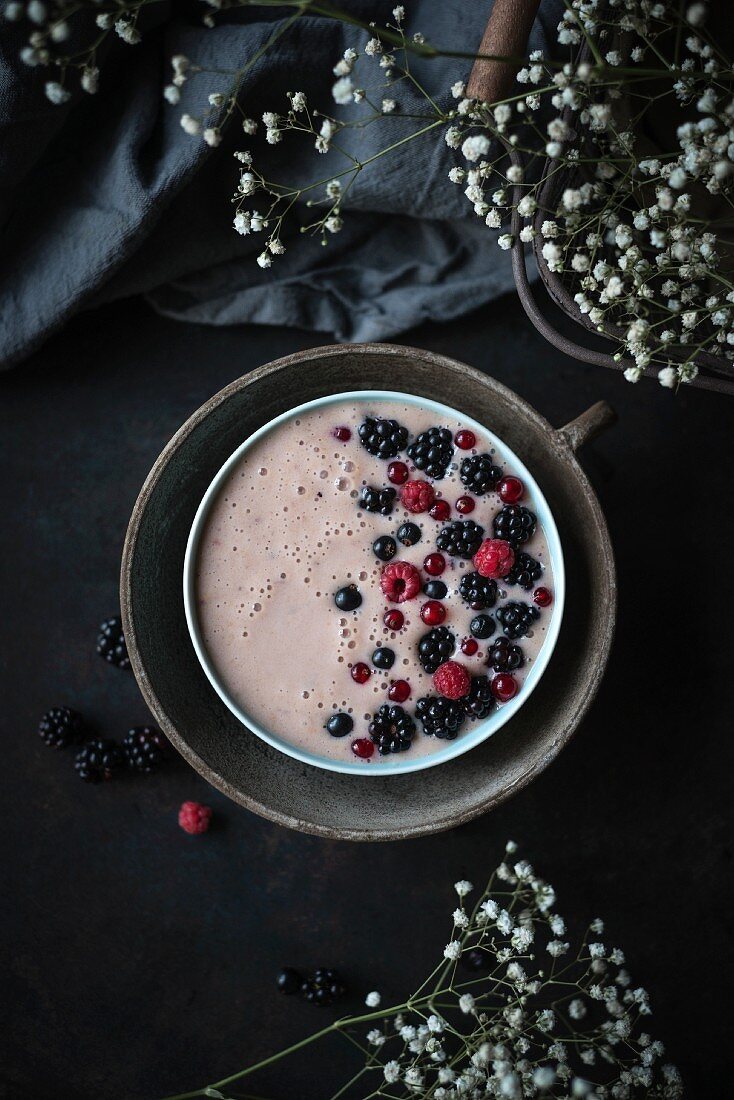 A vegan banana and raspberry smoothie bowl topped with blackcurrants, raspberries and redcurrants