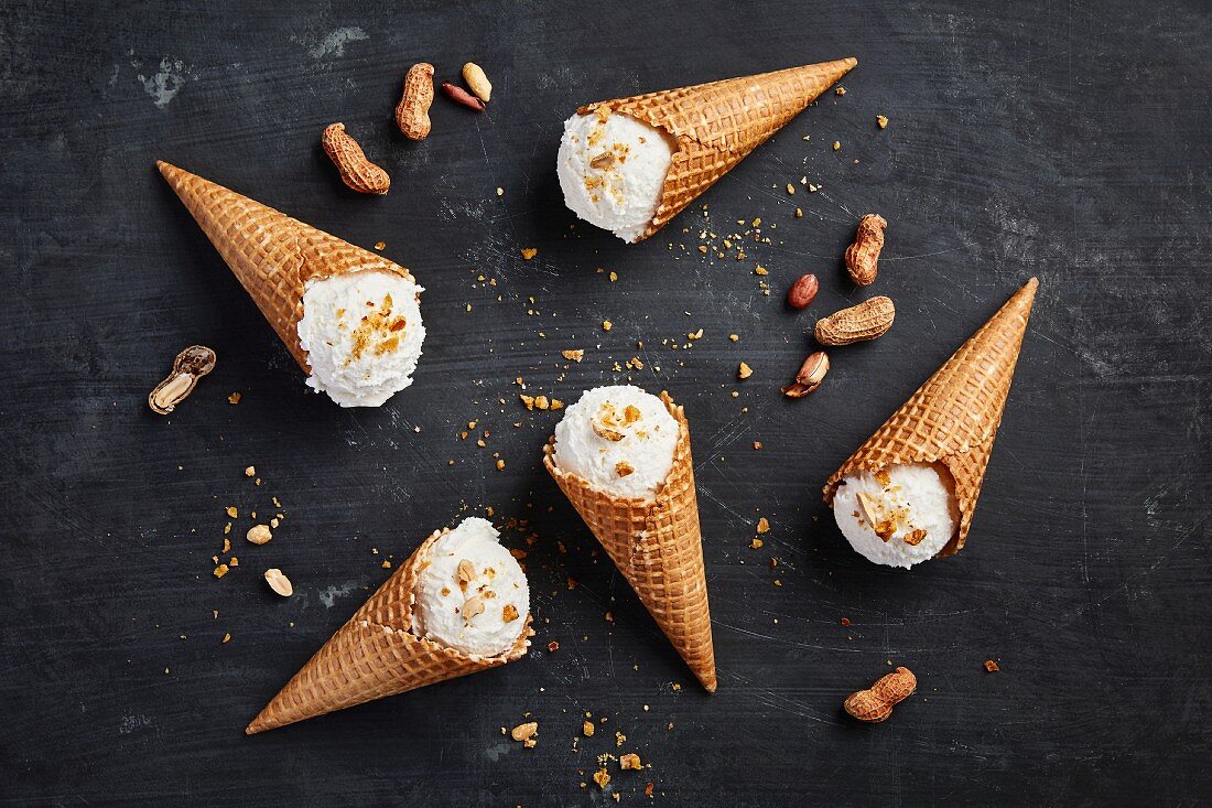 Banana and coconut ice cream in cones next to peanuts