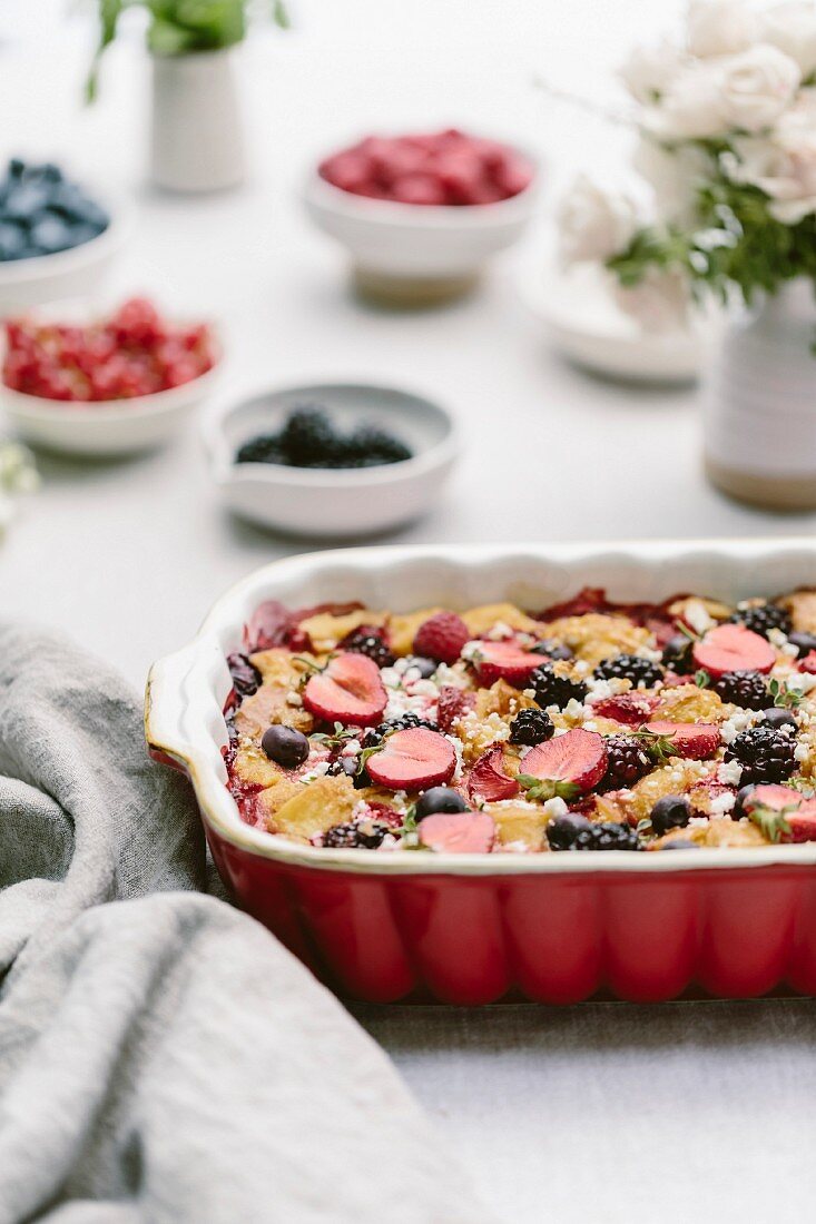 A goat's cheese and berry bread pudding in an ovenproof dish on a table