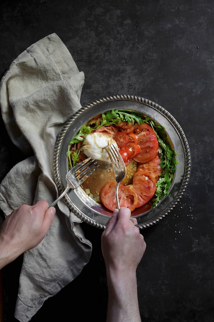 Caprese-Salat mit Tomaten, Mozzarella und Rucola auf silberner Servierplatte