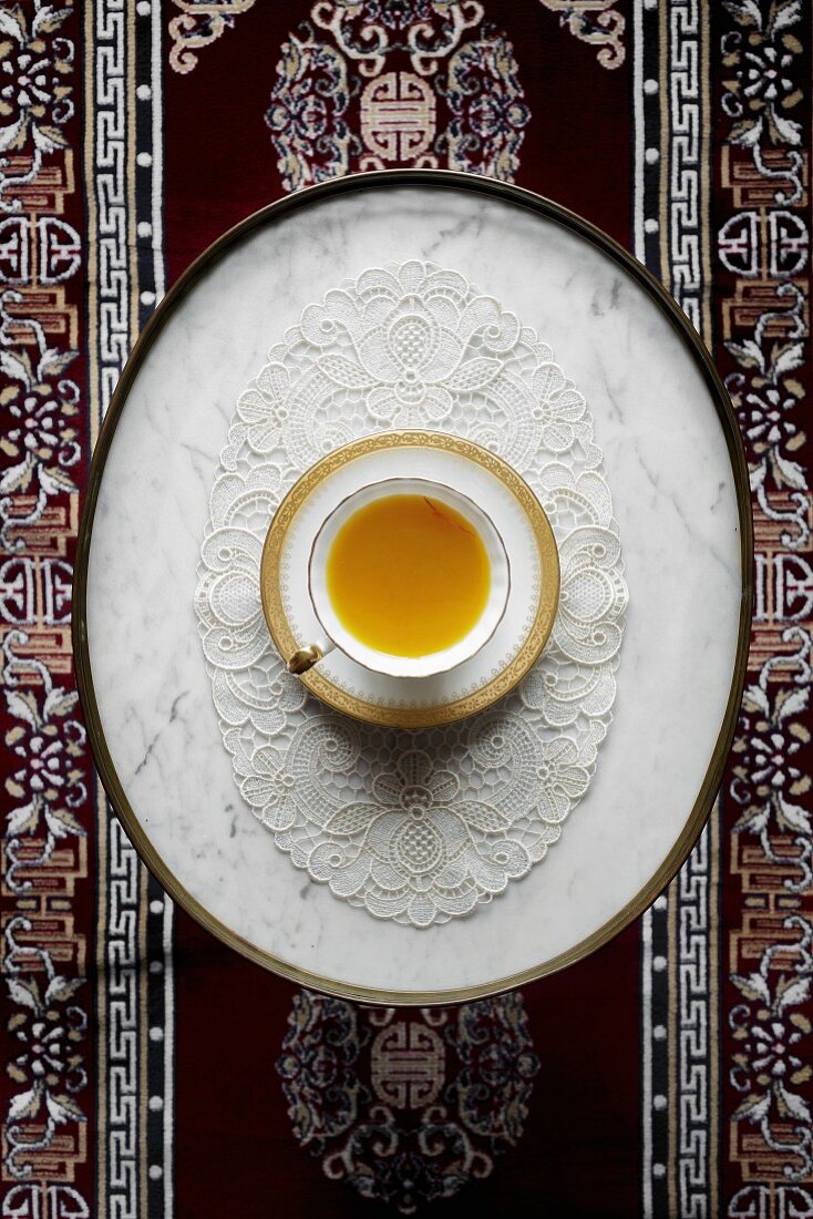 Eine Tasse Safran-Chai auf Spitzendeckchen (Aufsicht)