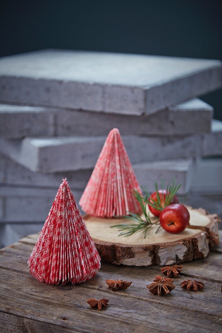 Kleine Tannenbäume aus rot-weißem Papier auf einer Holzscheibe