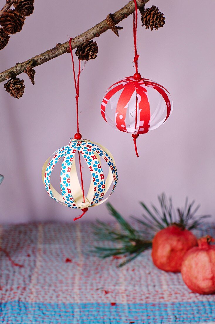 Christmas-tree baubles made from paper strips hung from larch branches