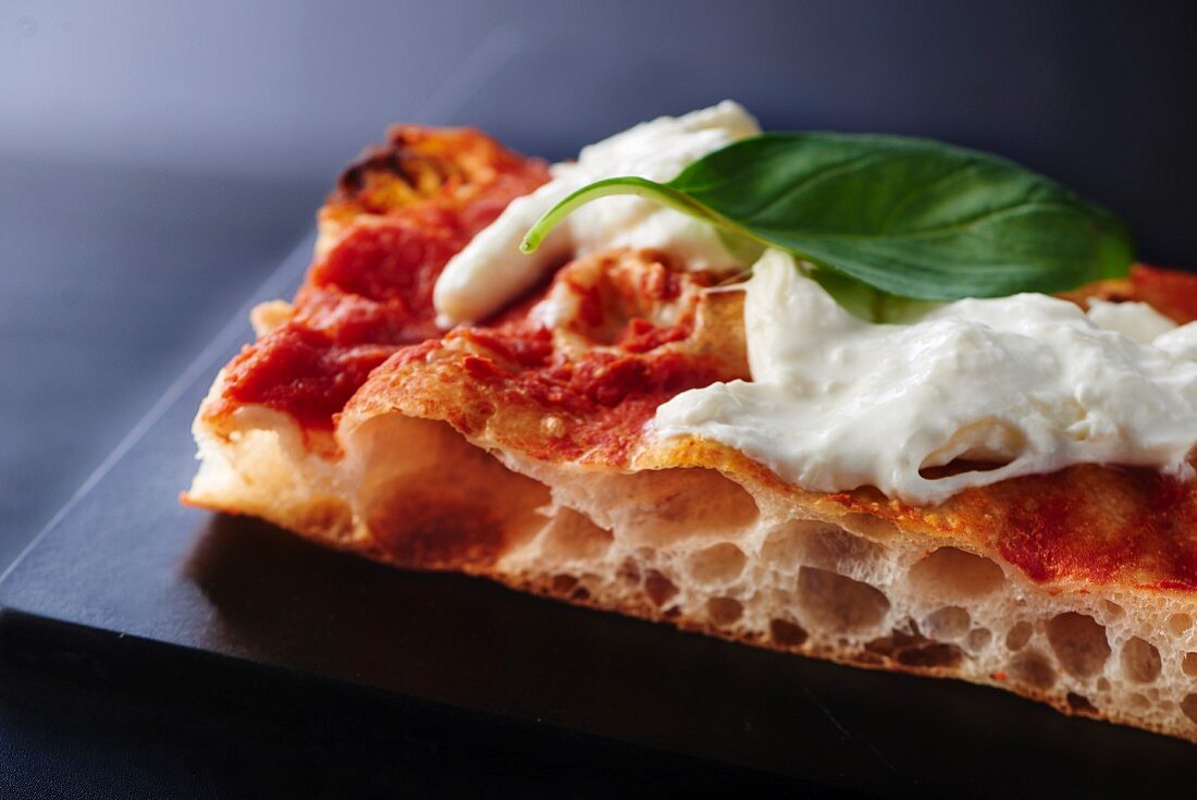 A slice of tomato, burrata and basil pizza