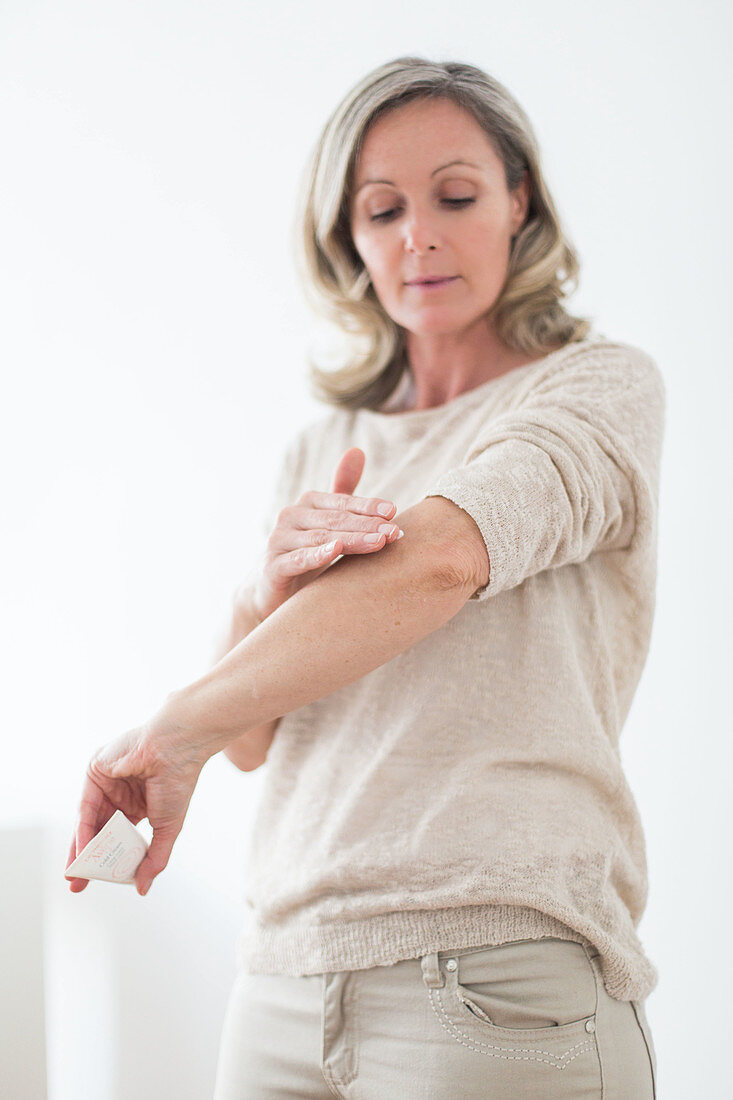 Woman applying cream on her elbow