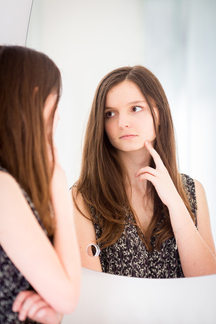 Teenage girl checking her face in the mirror