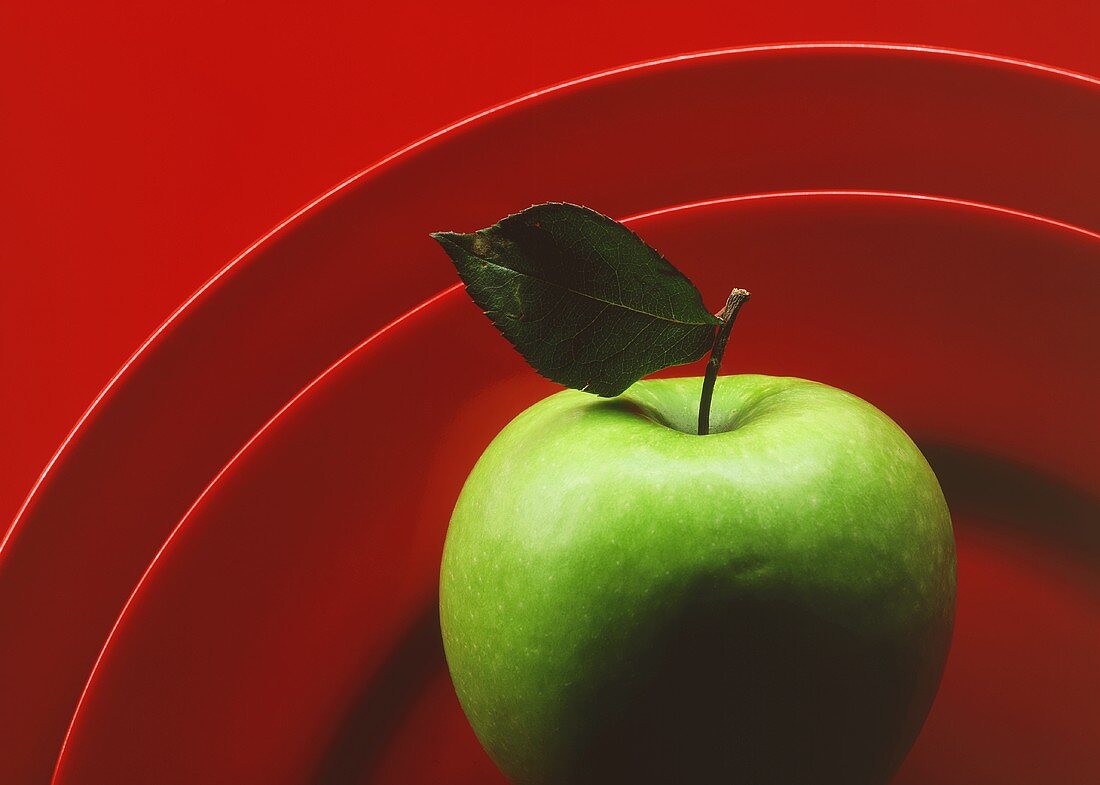 Granny Smith Apple with Leaf on Red Plate