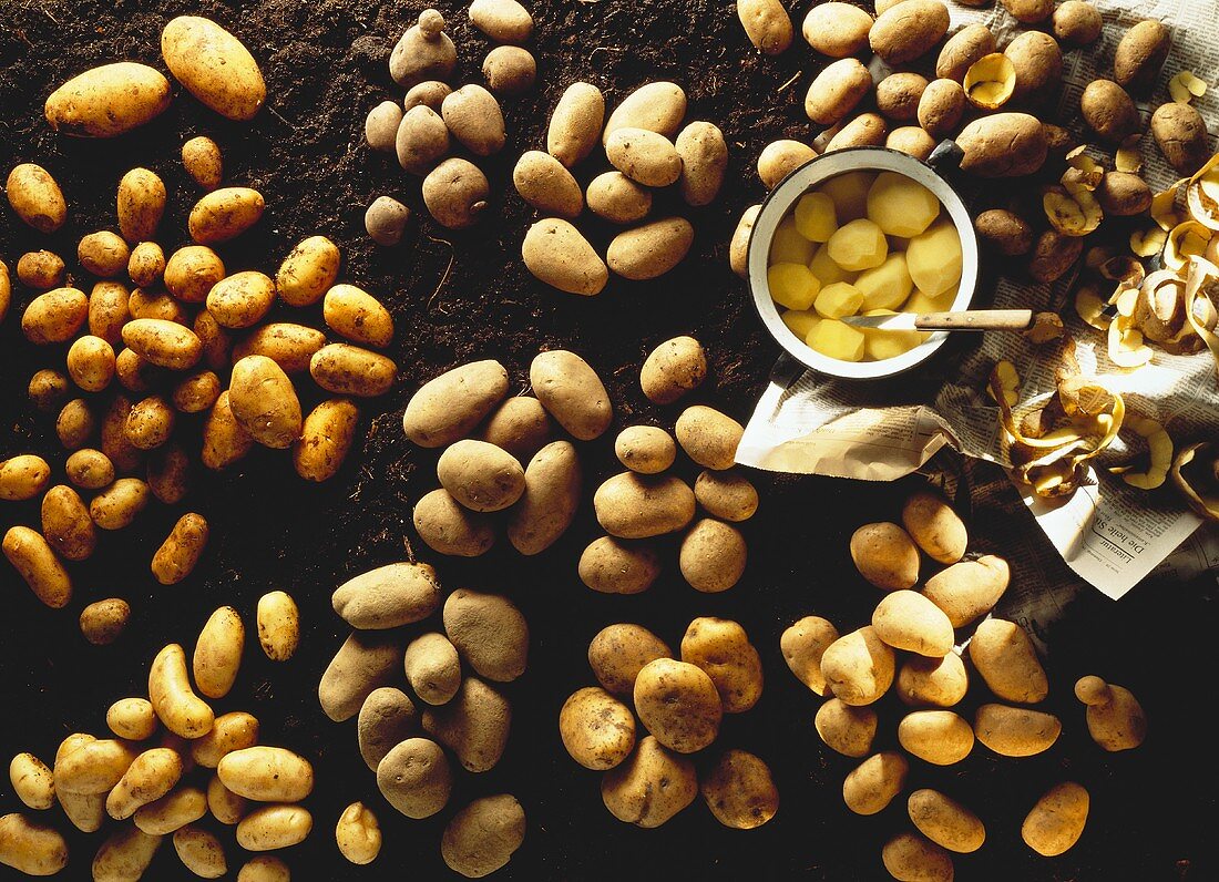 Several Assorted Whole Potatoes; Some Peeled in a Bowl