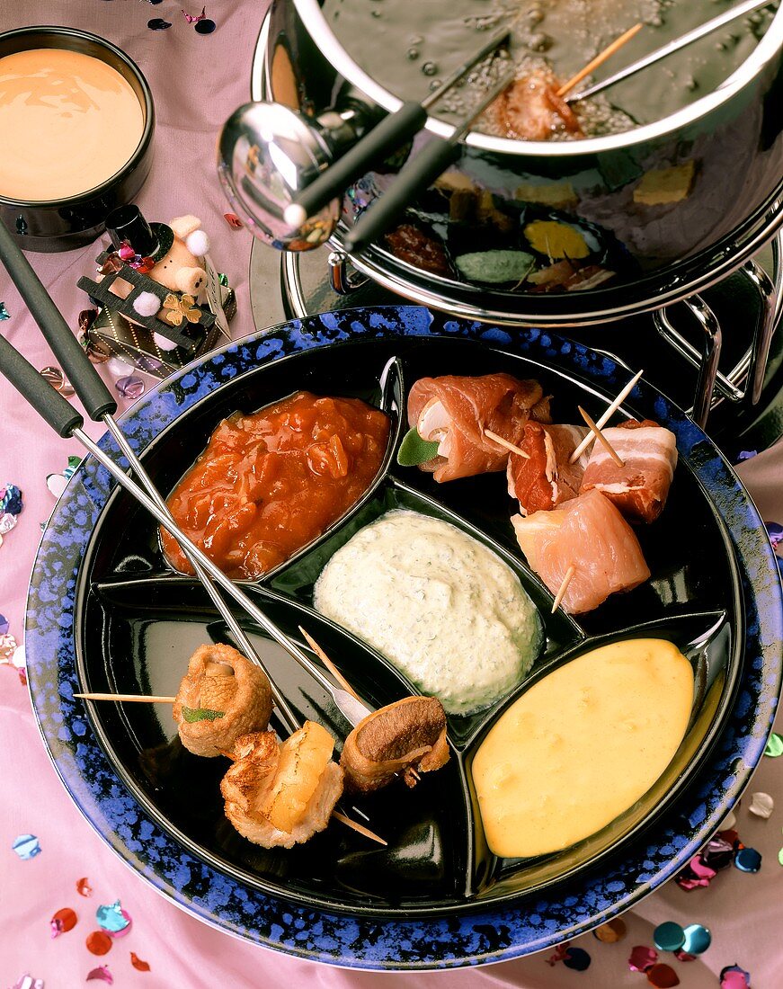 Fondue with various meats on skewers and sauces